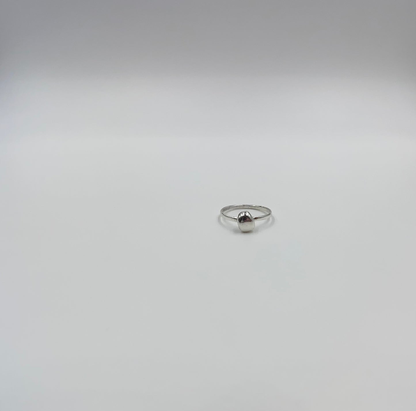 Organic sterling silver ring with large bump of silver resembling a raindrop as the focal, super simple straight band.