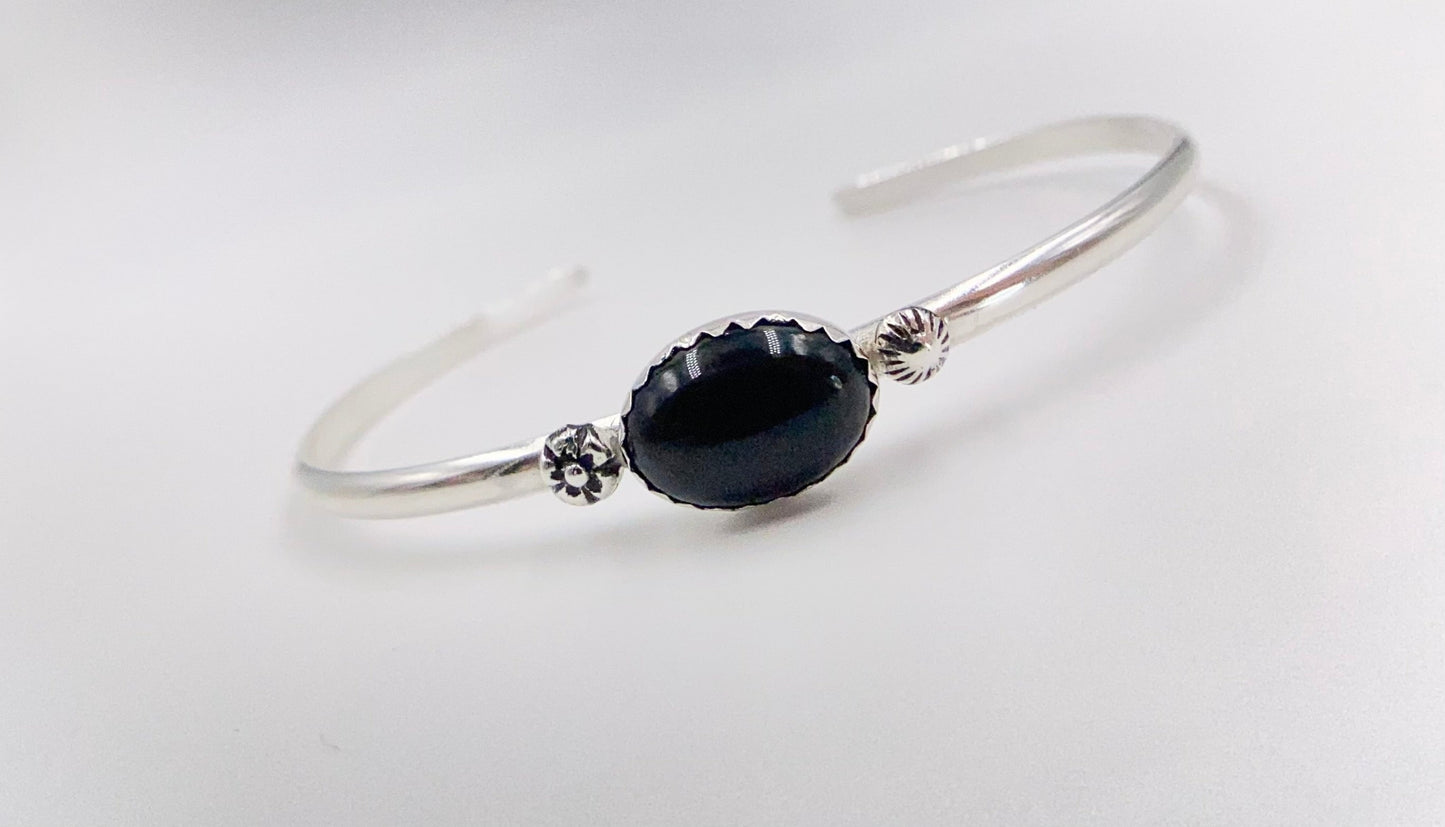 Stacakble cuffs with onyx, lapis or just a plain bracelet. Ornate pieces of silver dot the pieces as well as a oval stone.