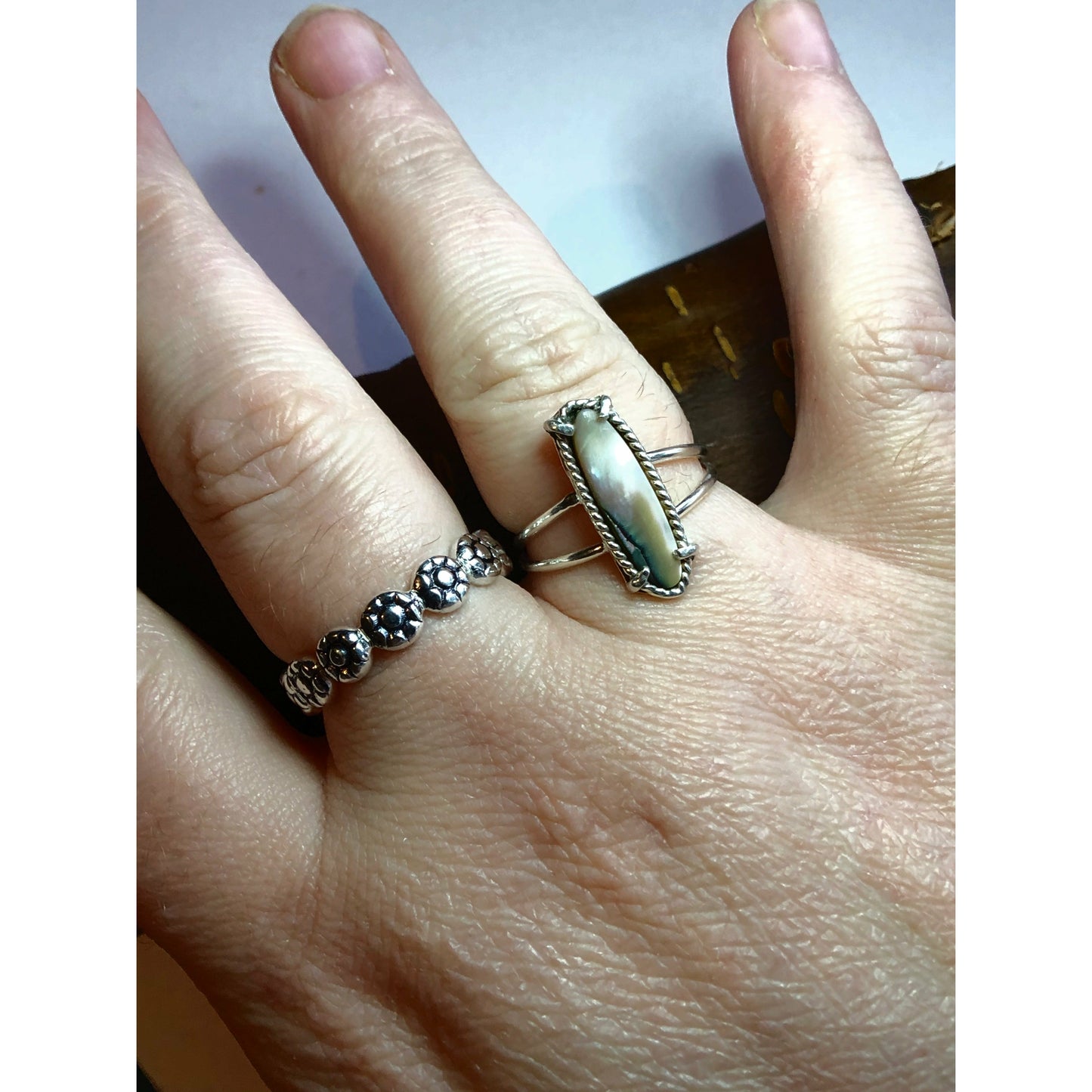 Flat square shaped ring with flowers imprinted on ring face. Repeat pattern all the way around.
