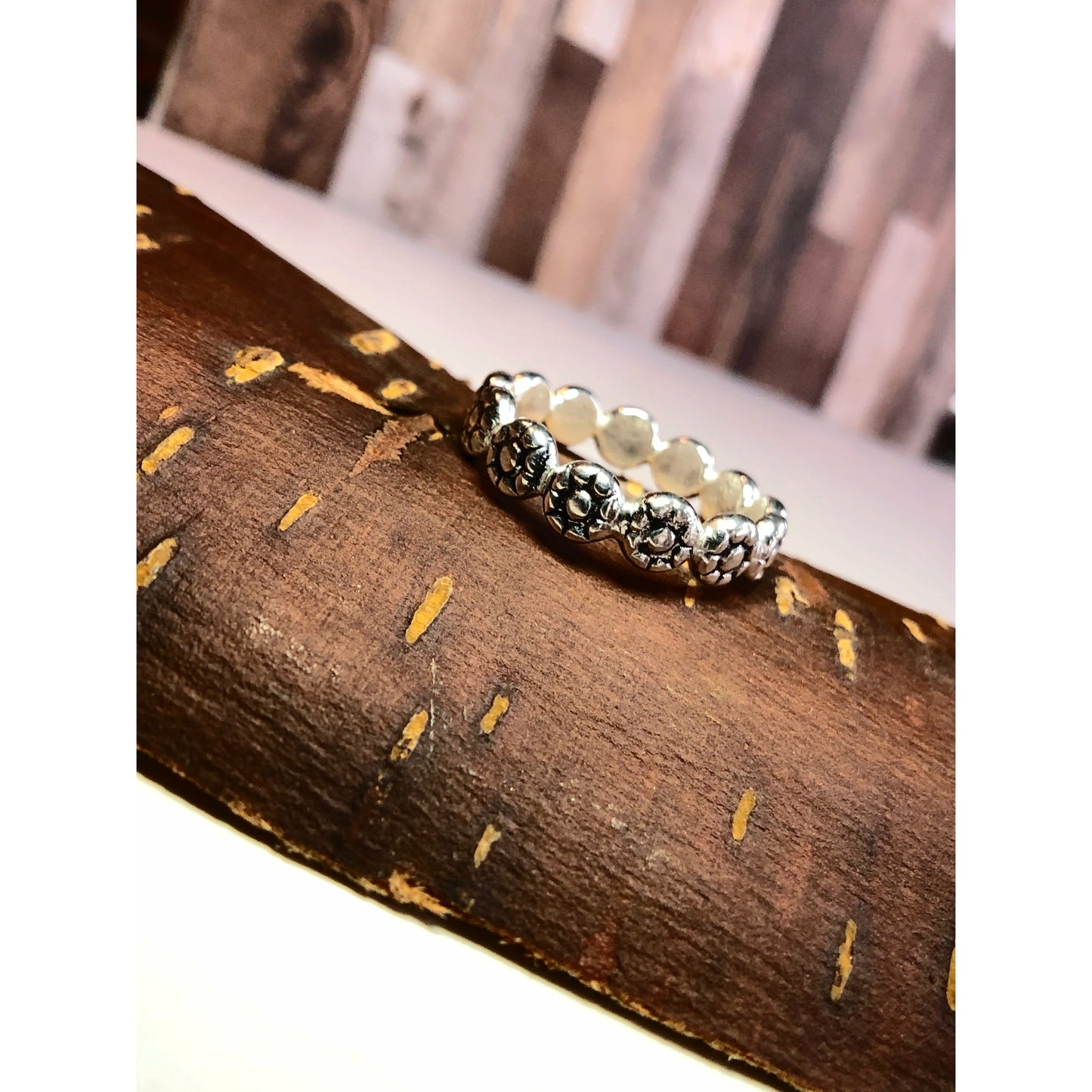 Flat square shaped ring with flowers imprinted on ring face. Repeat pattern all the way around.