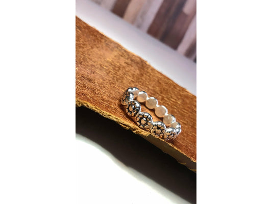 Flat square shaped ring with flowers imprinted on ring face. Repeat pattern all the way around.