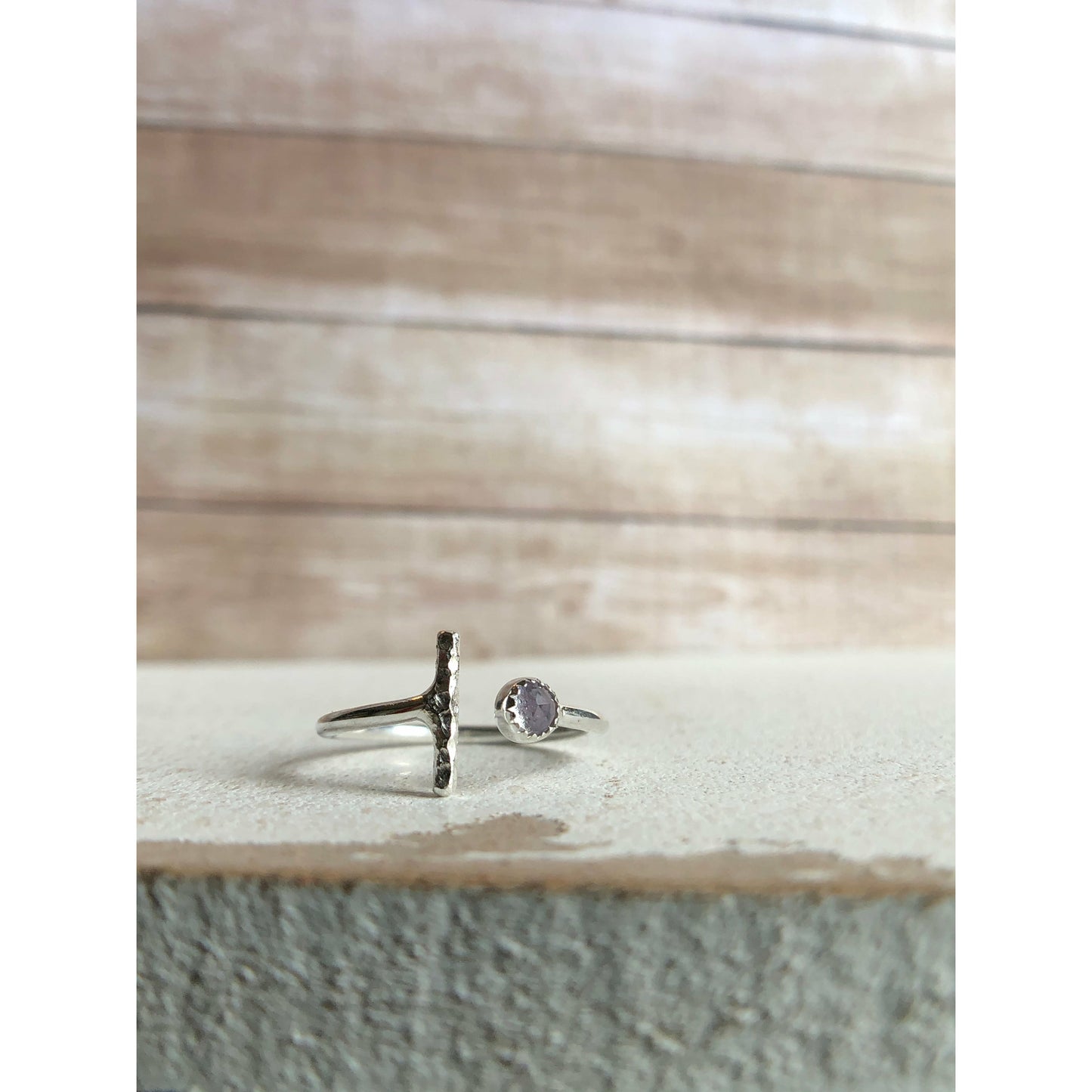 One side has a silver bar, other side of adjustable ring has a small stone purple in it.