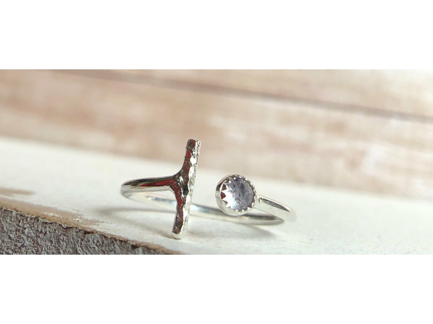 One side has a silver bar, other side of adjustable ring has a small stone purple in it.