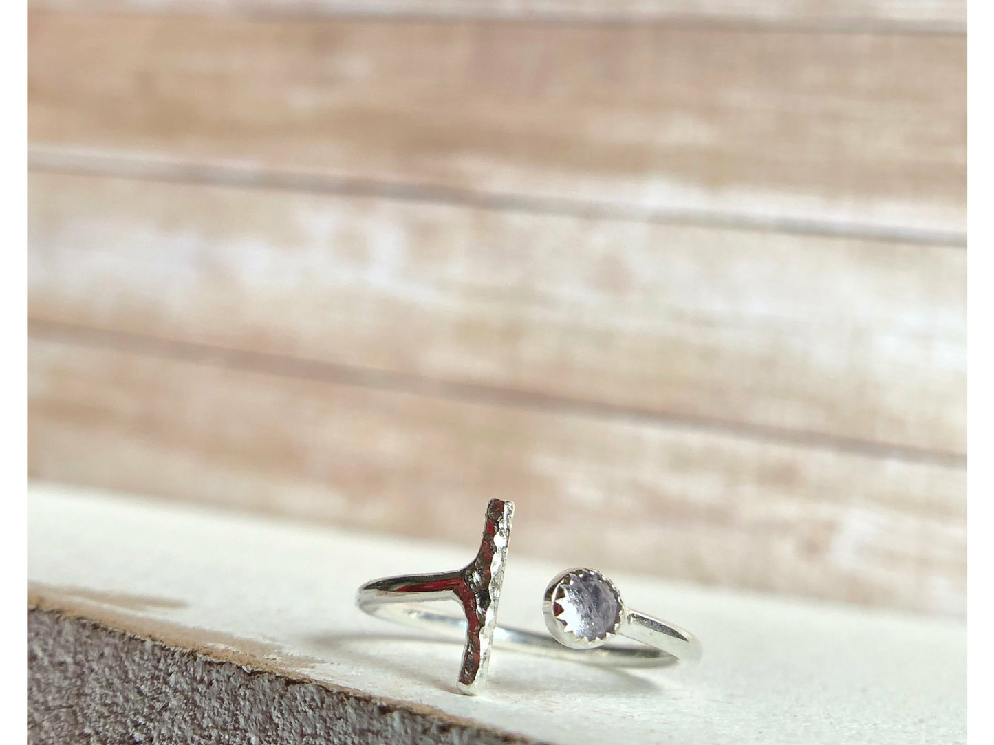 One side has a silver bar, other side of adjustable ring has a small stone purple in it.