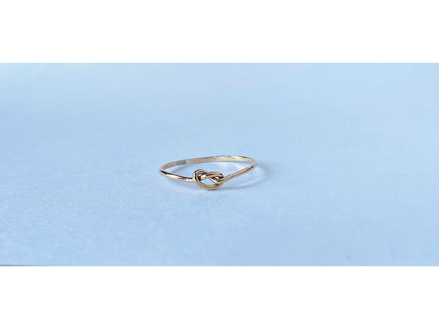 Silver round band twisted to form a small knot dead center of the ring. One continous piece of silver, no solder marks.