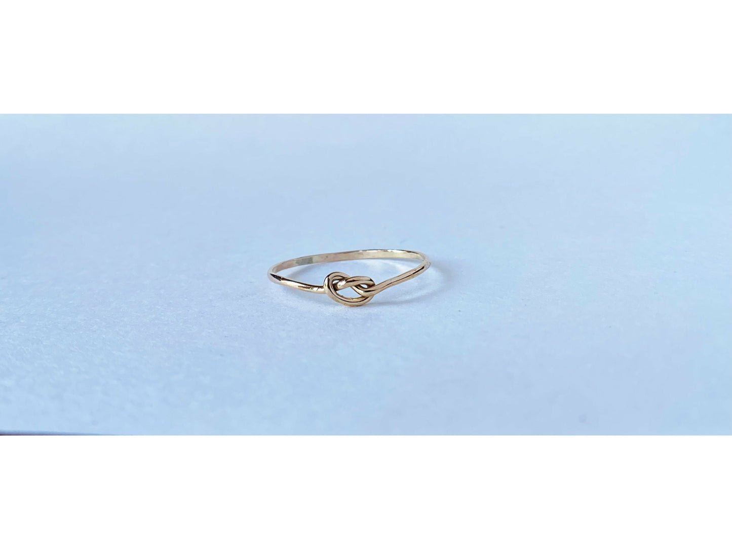 Silver round band twisted to form a small knot dead center of the ring. One continous piece of silver, no solder marks.