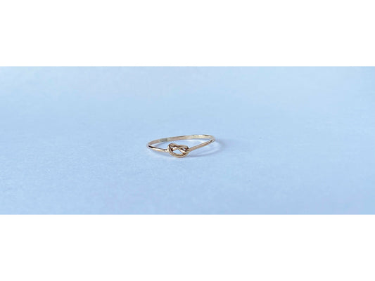 Silver round band twisted to form a small knot dead center of the ring. One continous piece of silver, no solder marks.