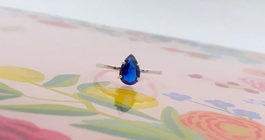 4 Prong set blue faceted teardrop stone, mounted on a square profile ring band