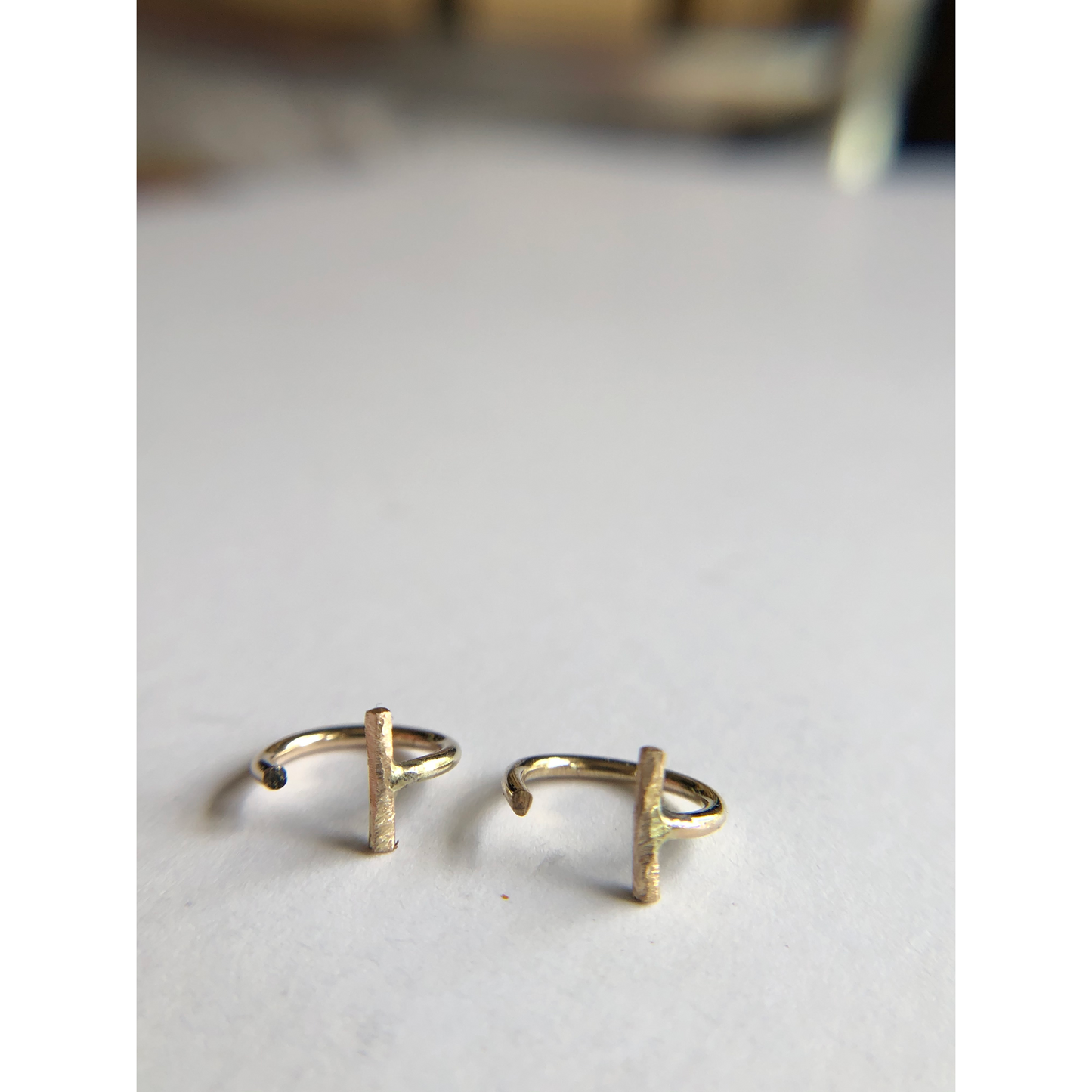 small gold half hoops with bar on one side (ear side) hugs close to ears