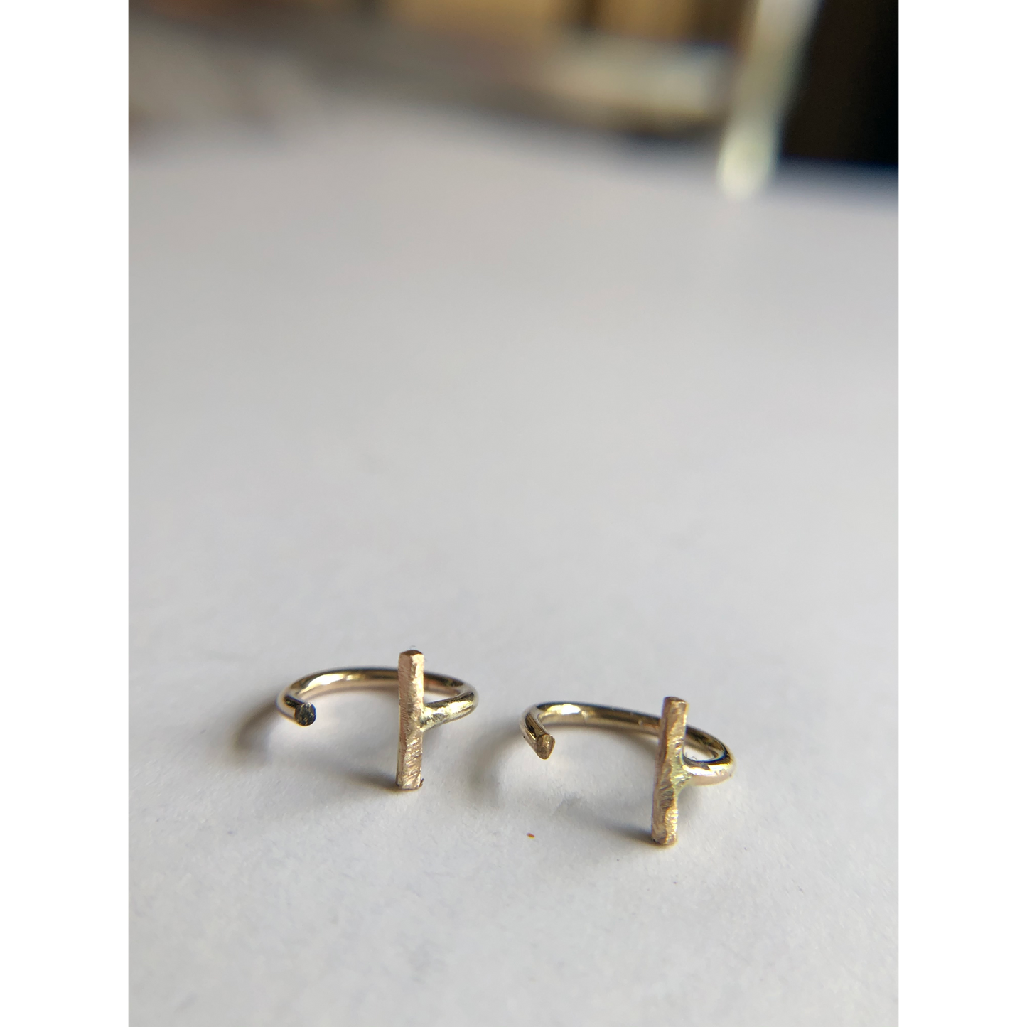 small gold half hoops with bar on one side (ear side) hugs close to ears