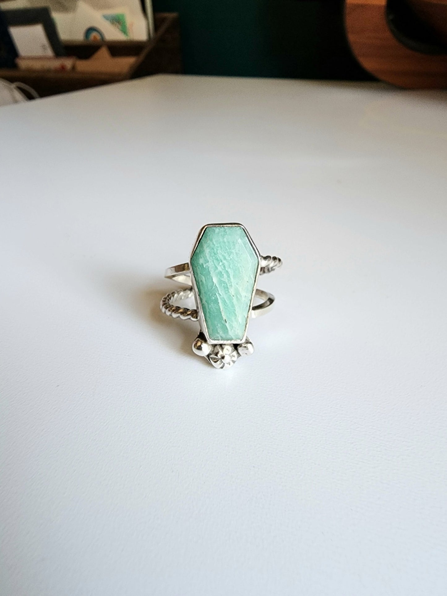 Amazonite coffin stone ring size 7 1/4 split shank with patterned twisted silver on top right and bottom left, square profile on top left and bottom right flower and small granulations on the left and right of small flower at bottom of stone. 