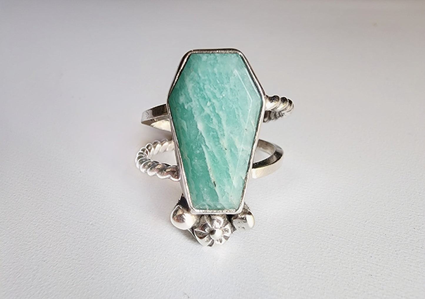 Amazonite coffin stone ring size 7 1/4 split shank with patterned twisted silver on top right and bottom left, square profile on top left and bottom right flower and small granulations on the left and right of small flower at bottom of stone. 