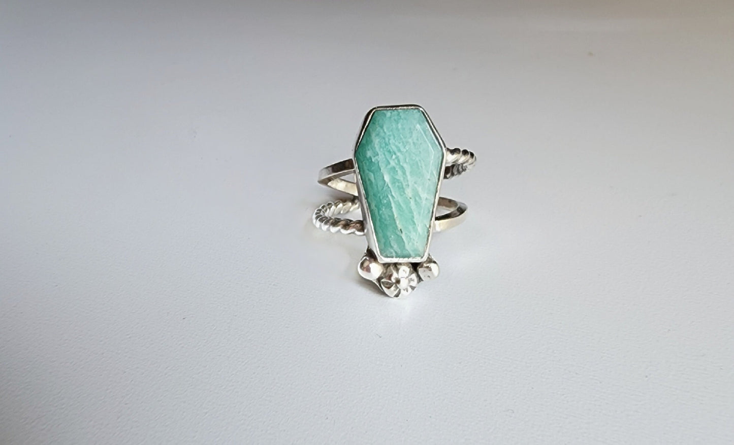 Amazonite coffin stone ring size 7 1/4 split shank with patterned twisted silver on top right and bottom left, square profile on top left and bottom right flower and small granulations on the left and right of small flower at bottom of stone. 