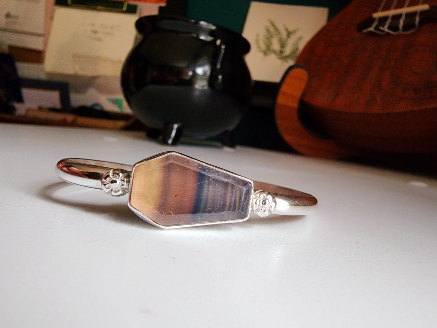 Fluorite coffin stone cuff with small botanical flowers on the left and right mounted on a sterling silver cuff