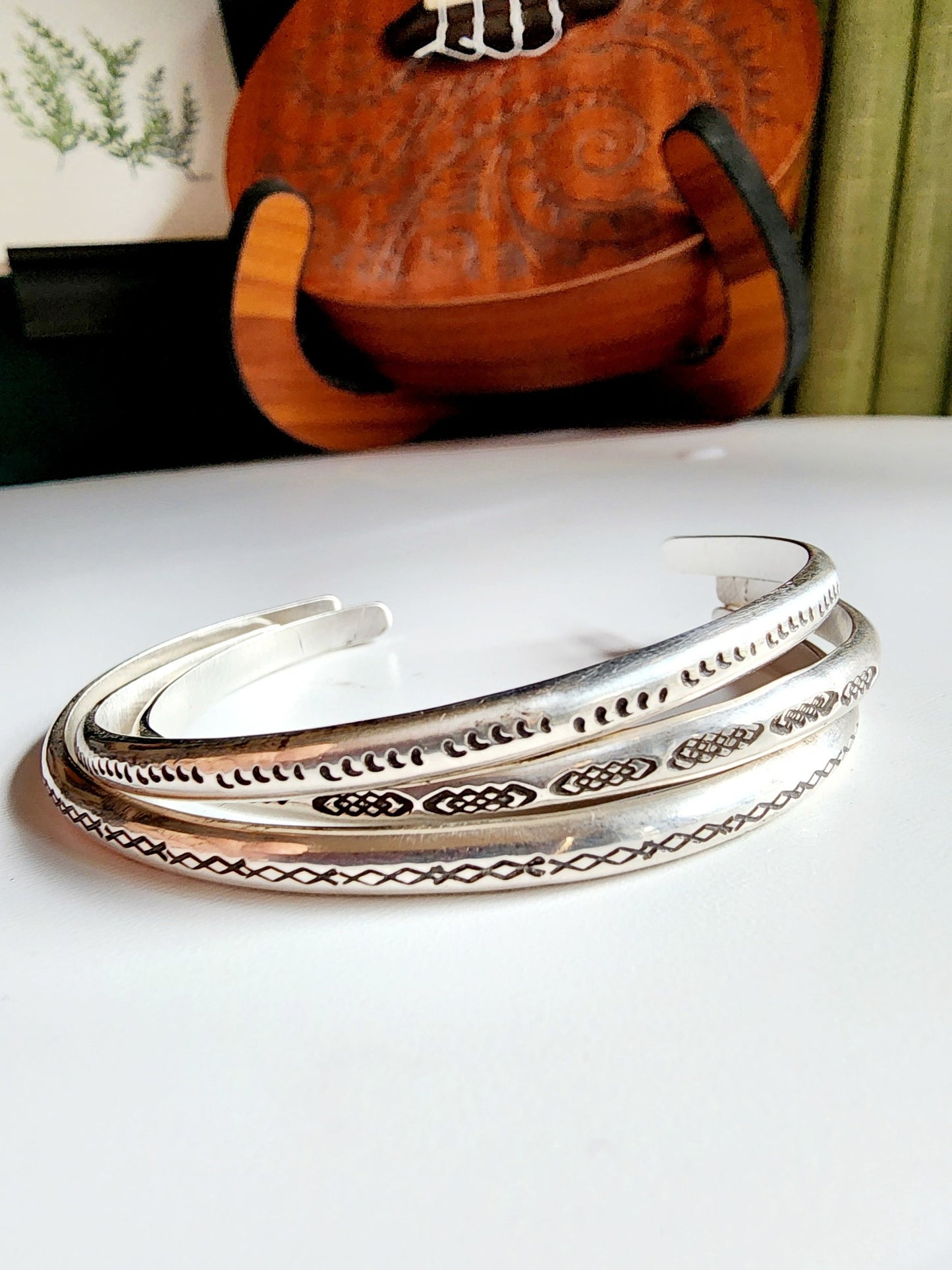 Stamped sterling silver cuff bracelet. Option one is a set of 5 small crescent moons, two is four interlocking triangles stamped continously, option 3 is four diamonds set right next to each other stamped continously.