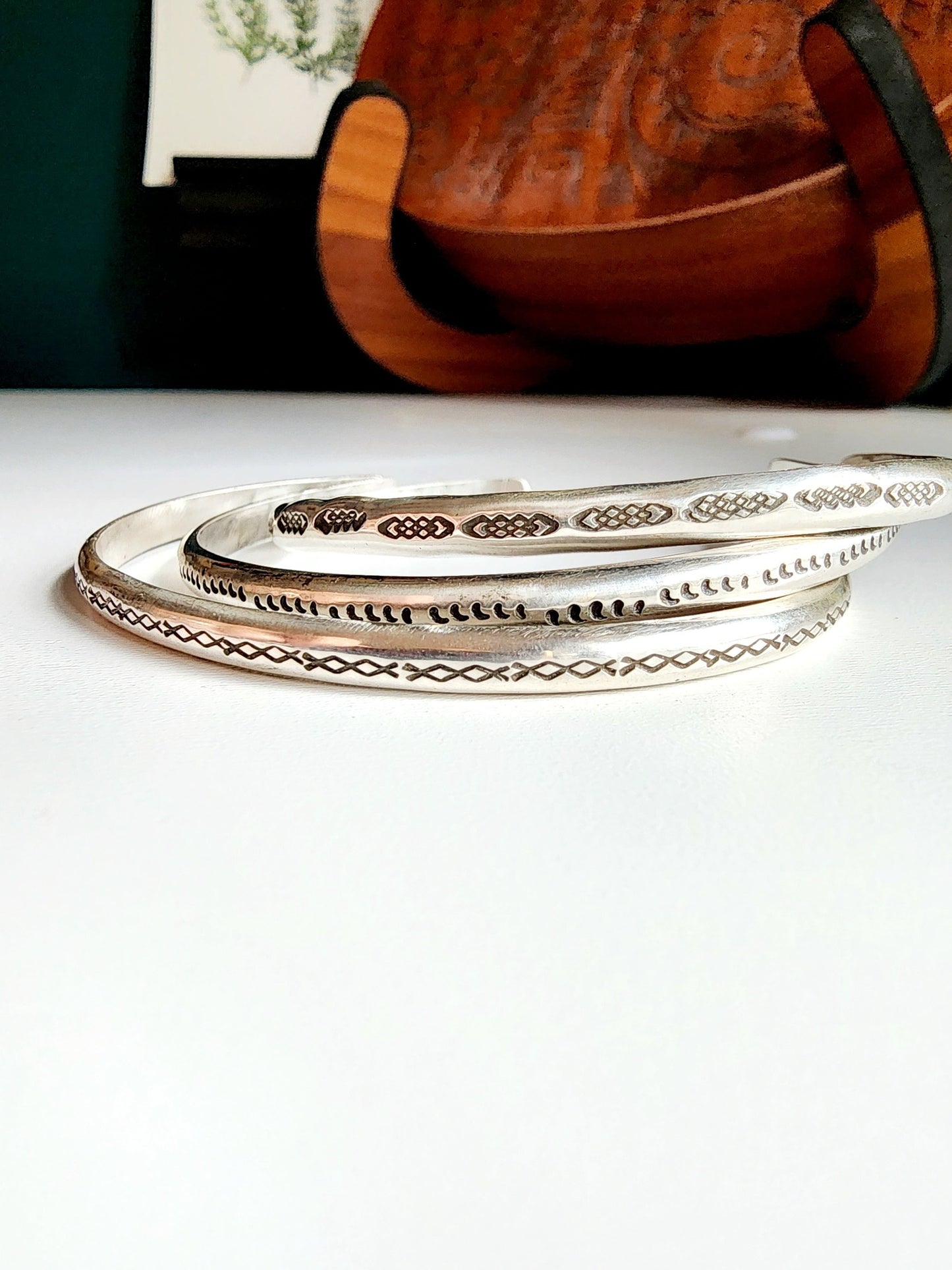 Stamped sterling silver cuff bracelet. Option one is a set of 5 small crescent moons, two is four interlocking triangles stamped continously, option 3 is four diamonds set right next to each other stamped continously.