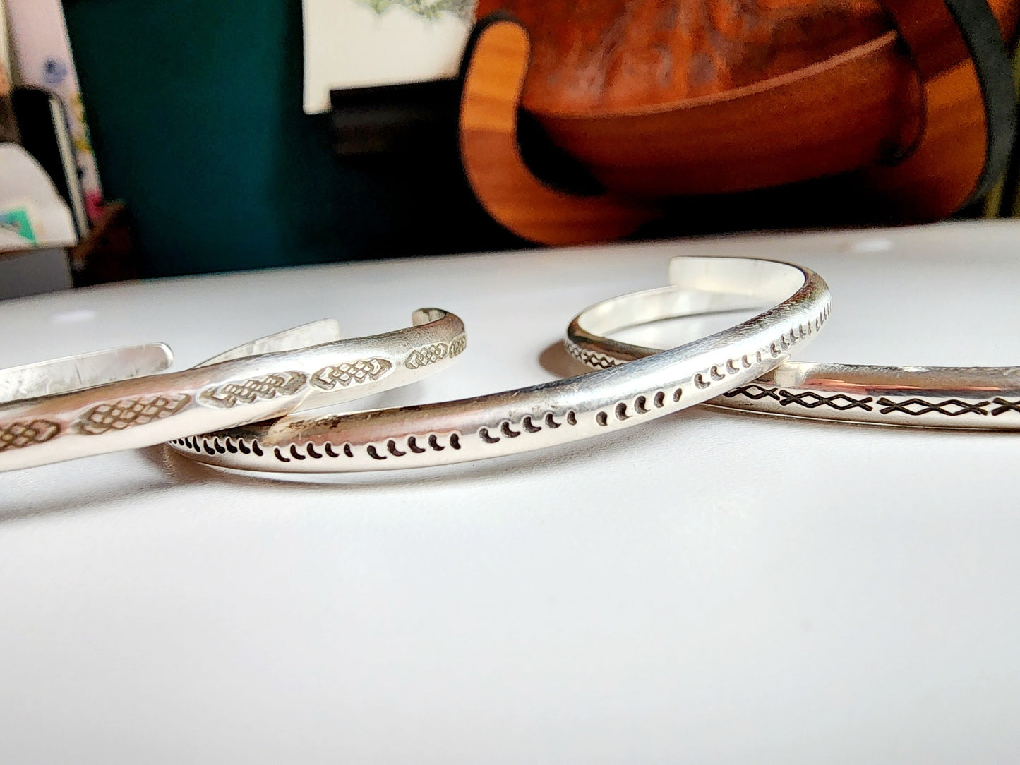 Stamped sterling silver cuff bracelet. Option one is a set of 5 small crescent moons, two is four interlocking triangles stamped continously, option 3 is four diamonds set right next to each other stamped continously.