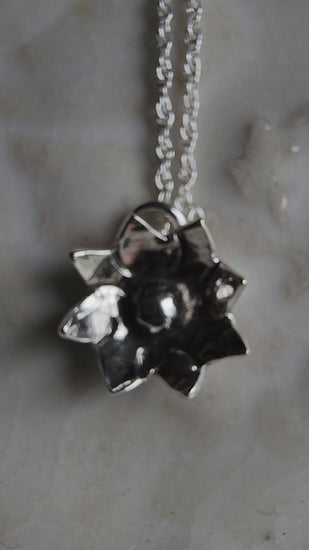 Tiny flower pendant hanging from a dainty silver chain