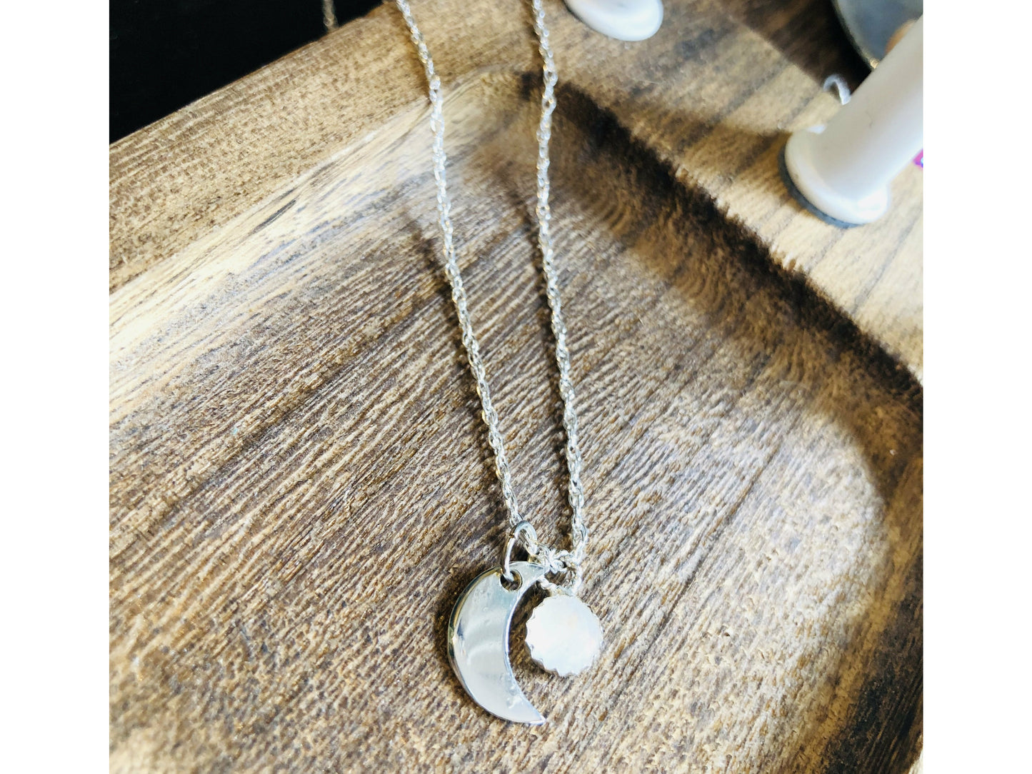 moon cut out of silver horns pointing down with a small moonstone dangling from the chain to overlap the moon.