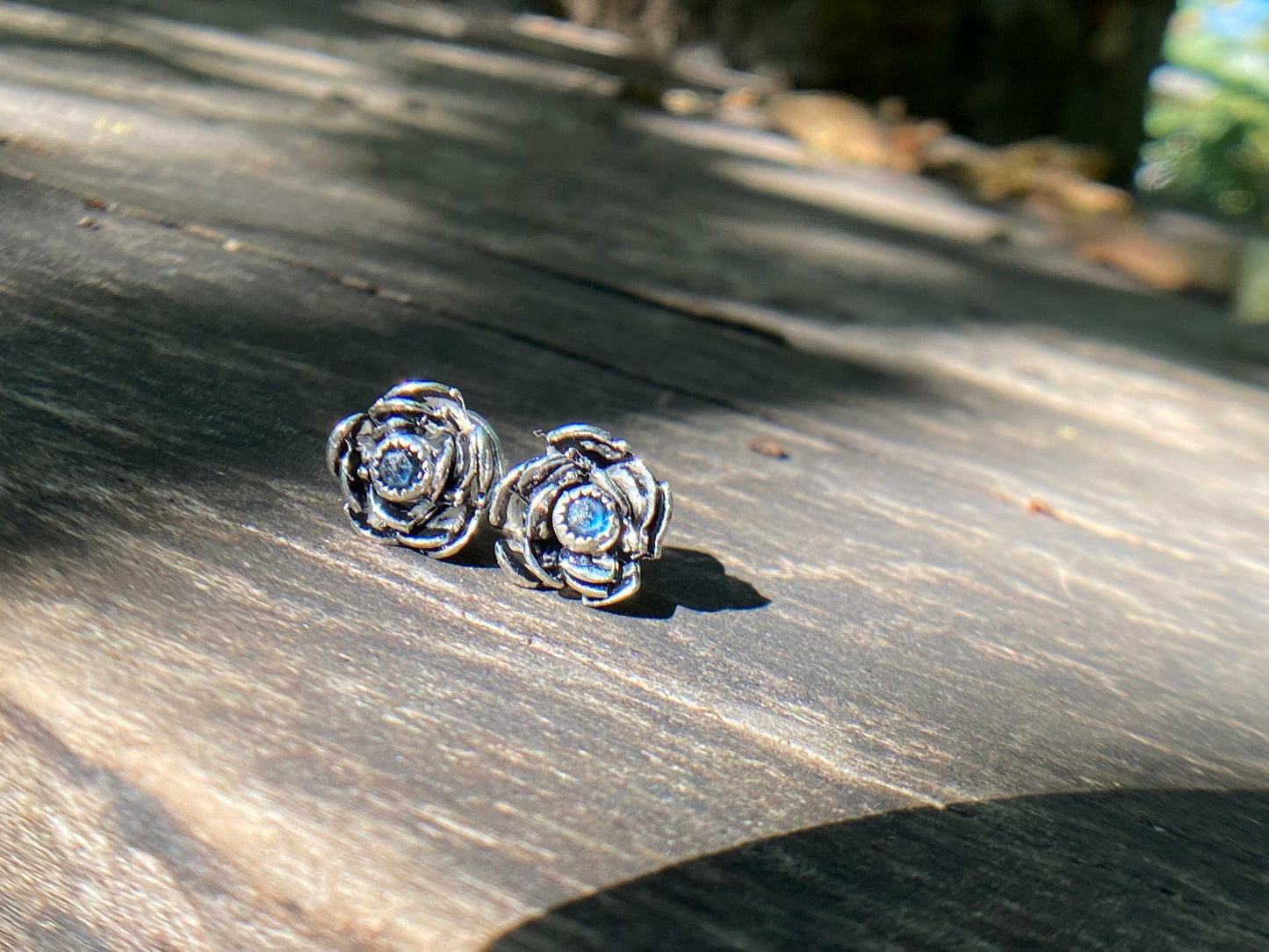 Rose wrapped silver around a small sapphire looking like the center of the bloom.