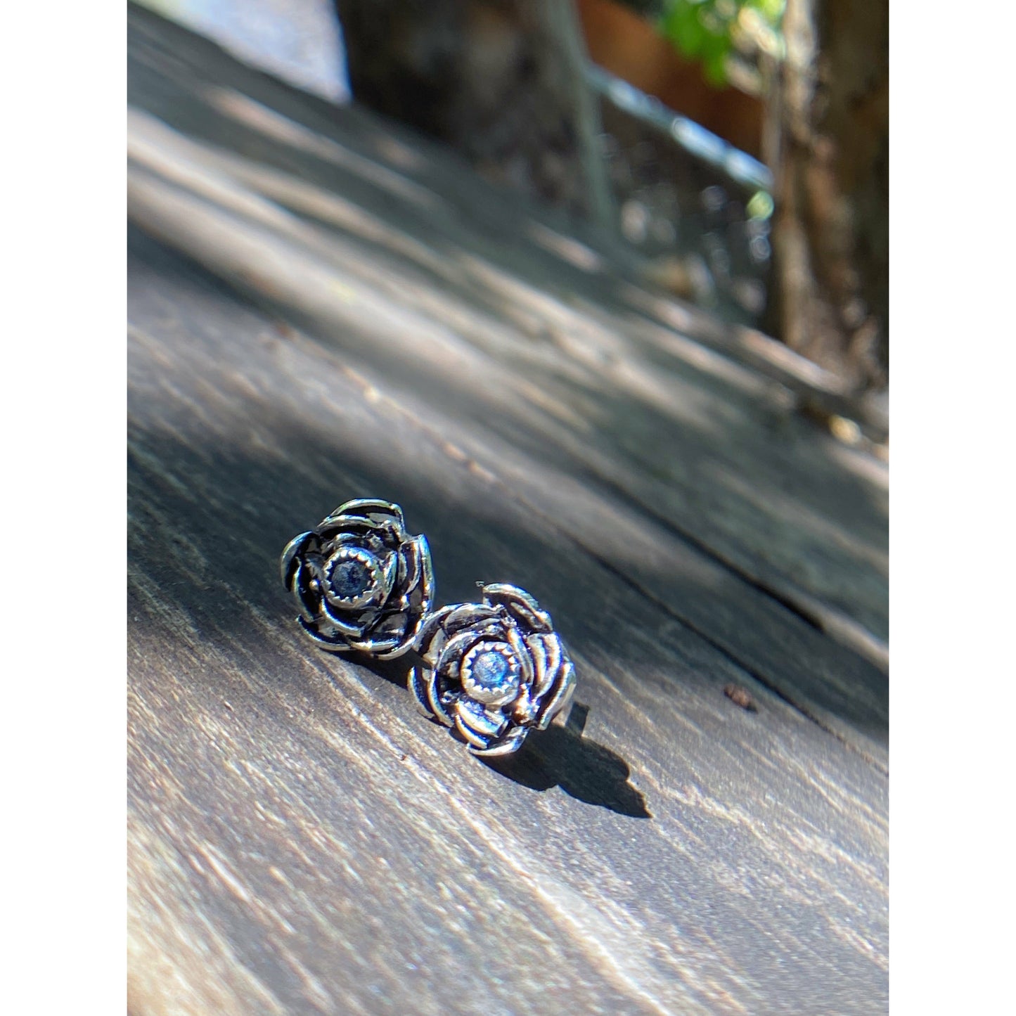 Rose wrapped silver around a small sapphire looking like the center of the bloom.