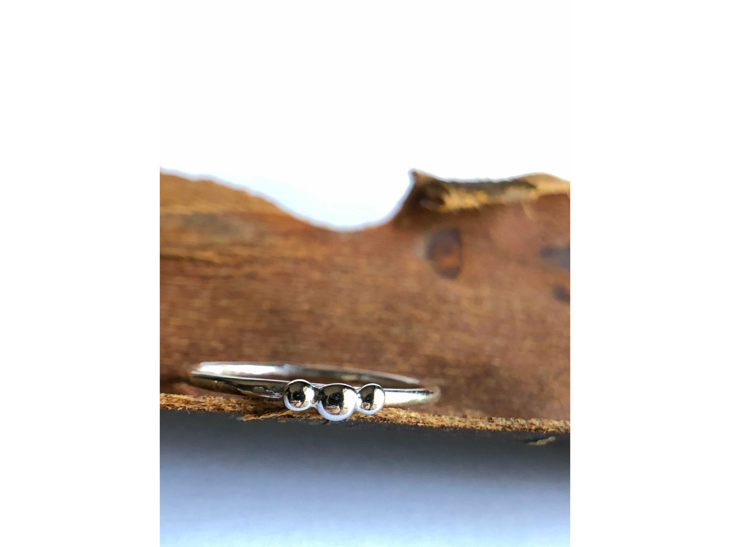 small dots of silver three in total as the focal of this rounded band ring.