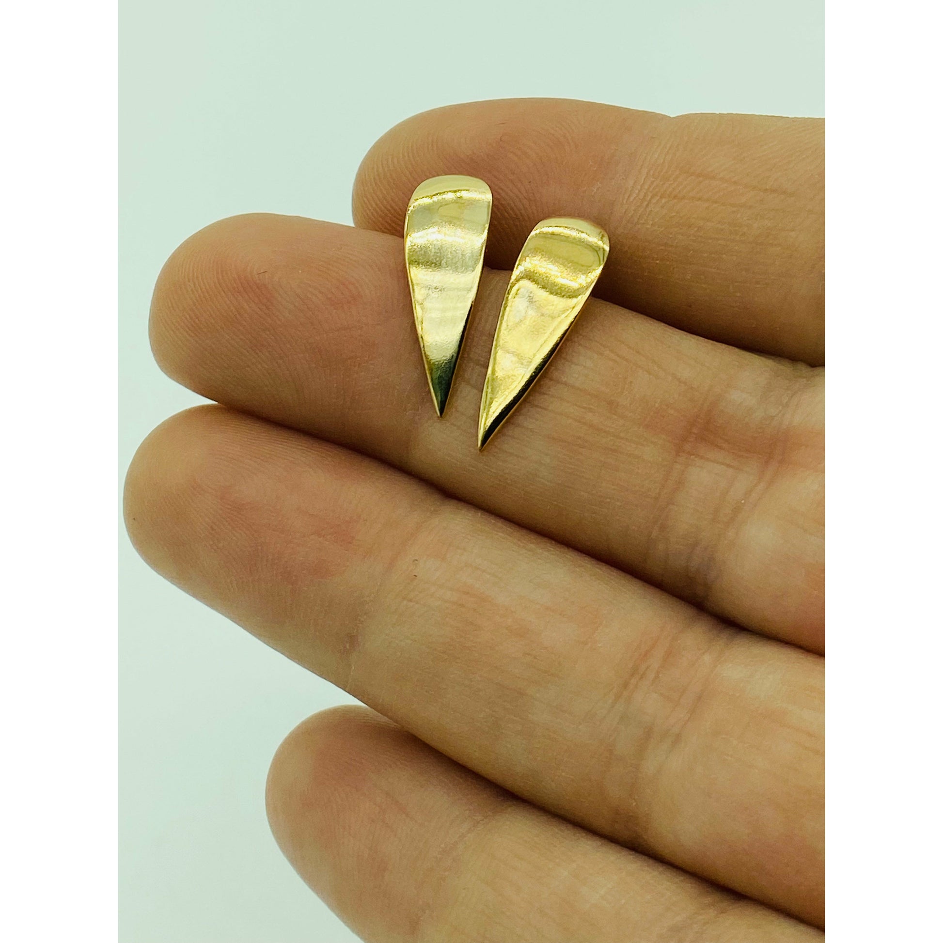 Gold spike earrings with point facing down.