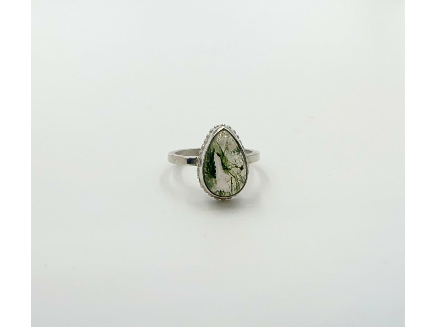 small green moss suspended in quartz, open bezel so light shines through mounted on a rounded simple band.