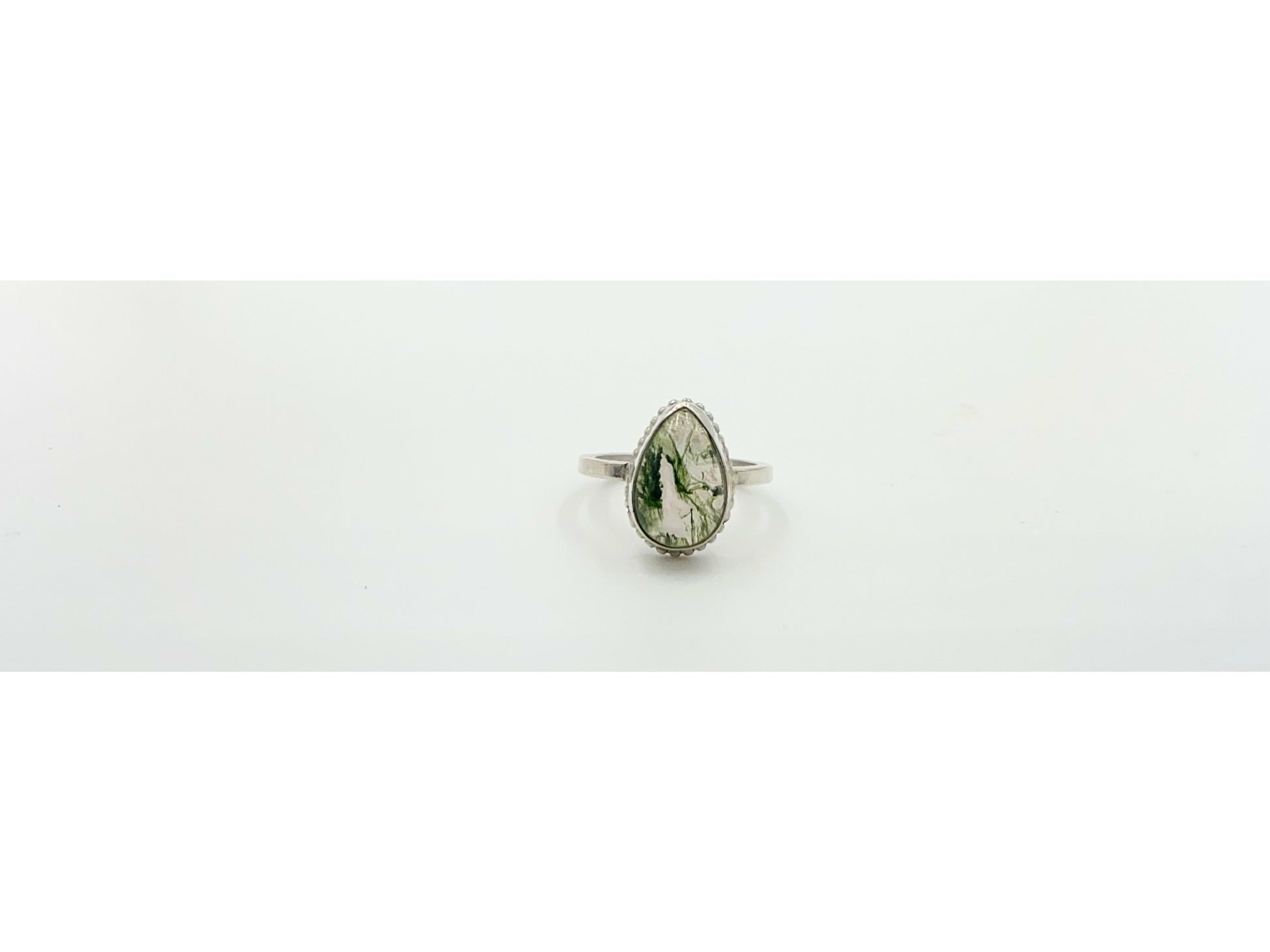 small green moss suspended in quartz, open bezel so light shines through mounted on a rounded simple band.