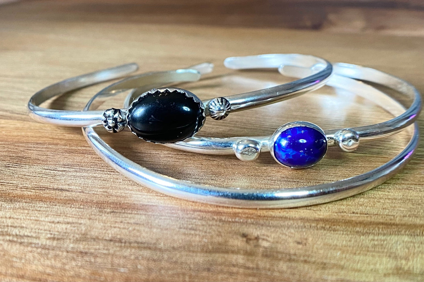 Stacakble cuffs with onyx, lapis or just a plain bracelet. Ornate pieces of silver dot the pieces as well as a oval stone.