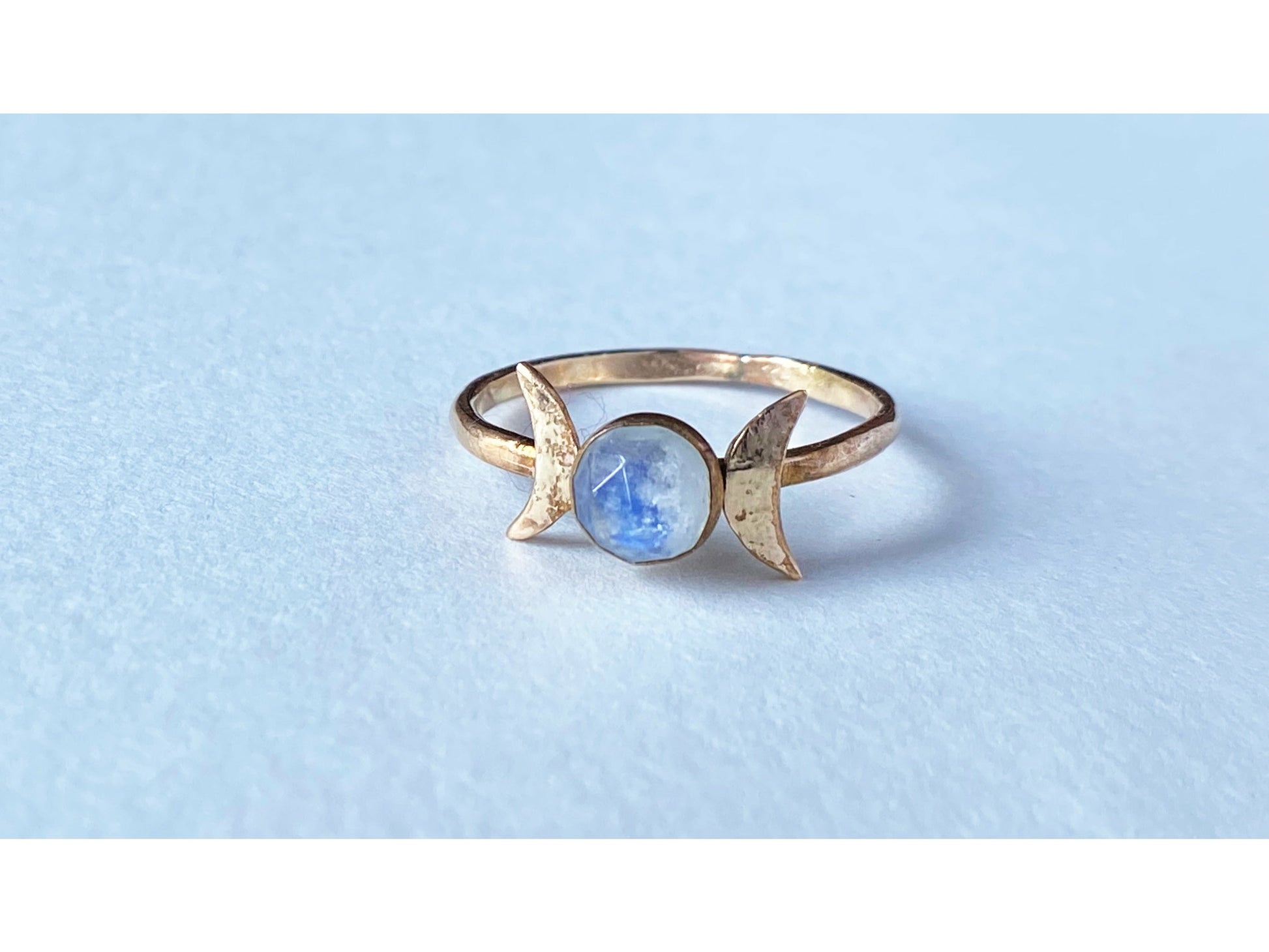 Two moons on the left and right of the stone, moonstone set at focal. Made out of gold filled.